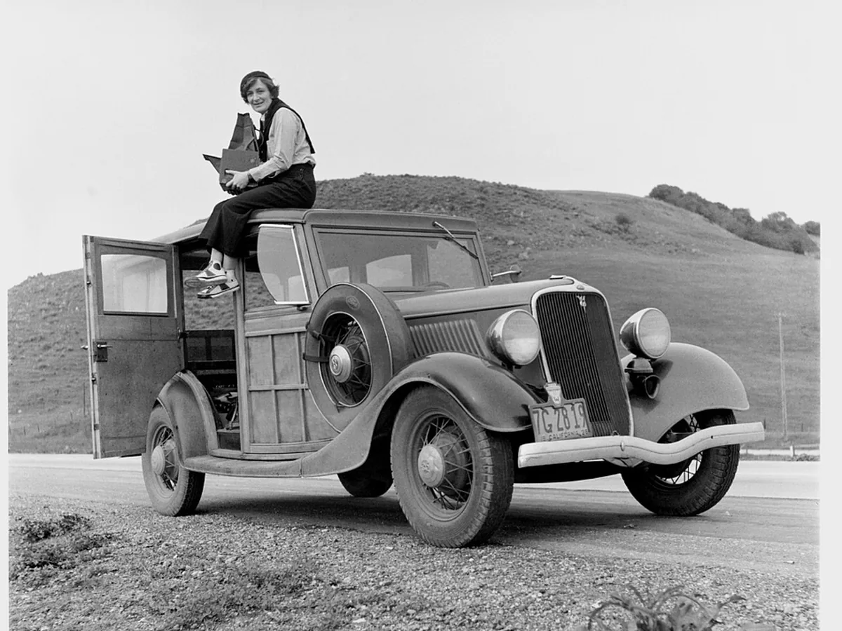 Black and white photo of a woman on a 1930s car, before enhancement
